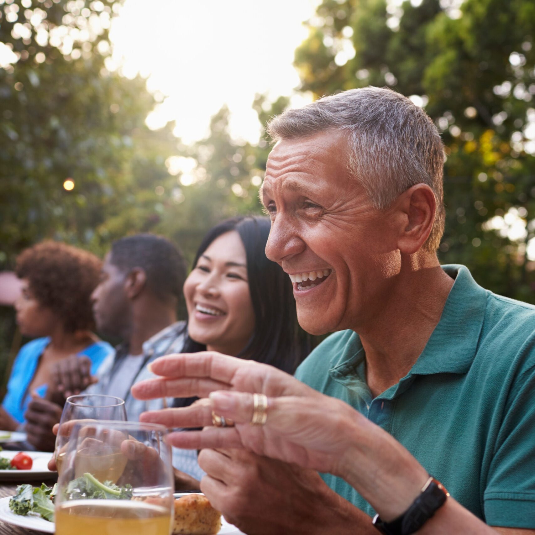 Group Of Mature Friends Enjoying Outdoor Meal In Backyard